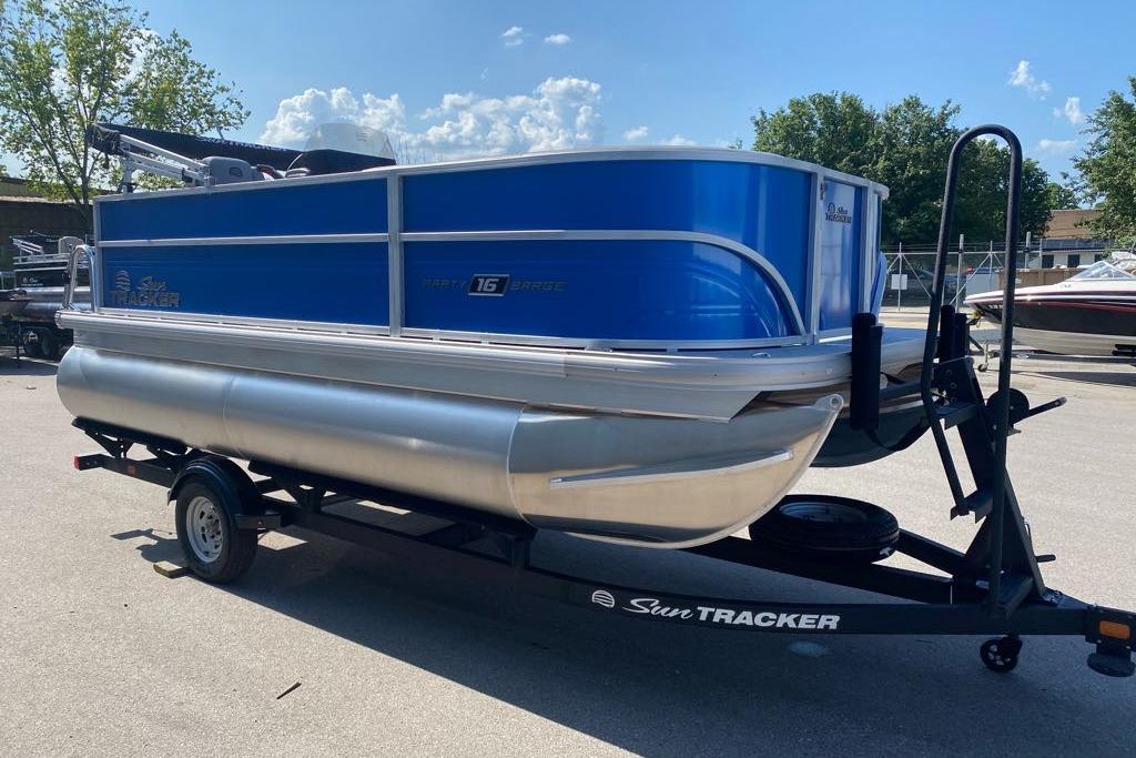 Sun Tracker Party Barge 16 DLX 2026 Sun Tracker Party Barge 16 DLX pontoon boat on trailer, parked outdoors.