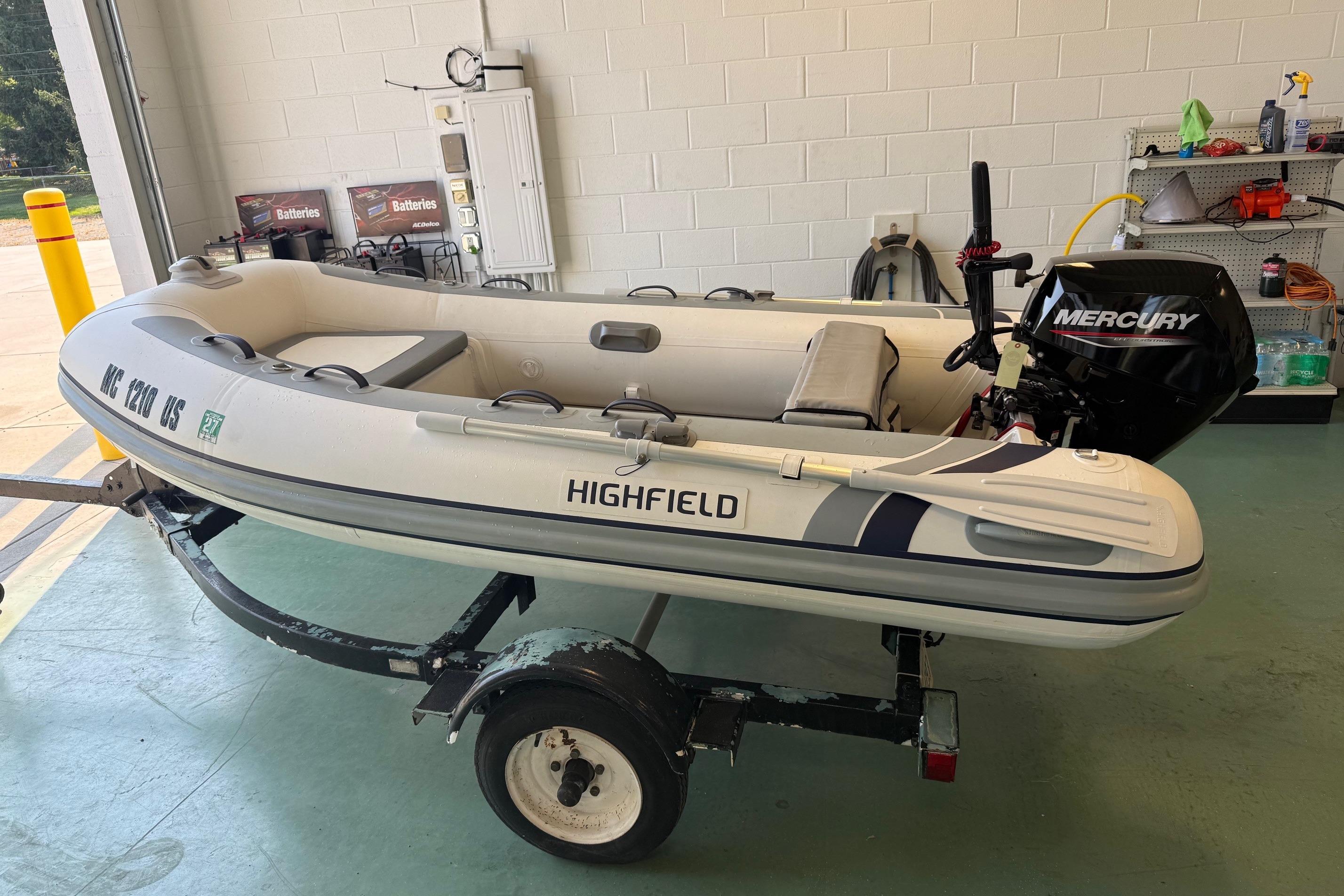 Highfield Classic 310 2022 Highfield Classic 310 inflatable boat with Mercury outboard motor on a trailer in a garage.