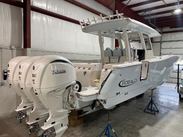 Robalo R360 Center Console 2023 Robalo R360 Center Console boat with triple Yamaha engines in a warehouse.