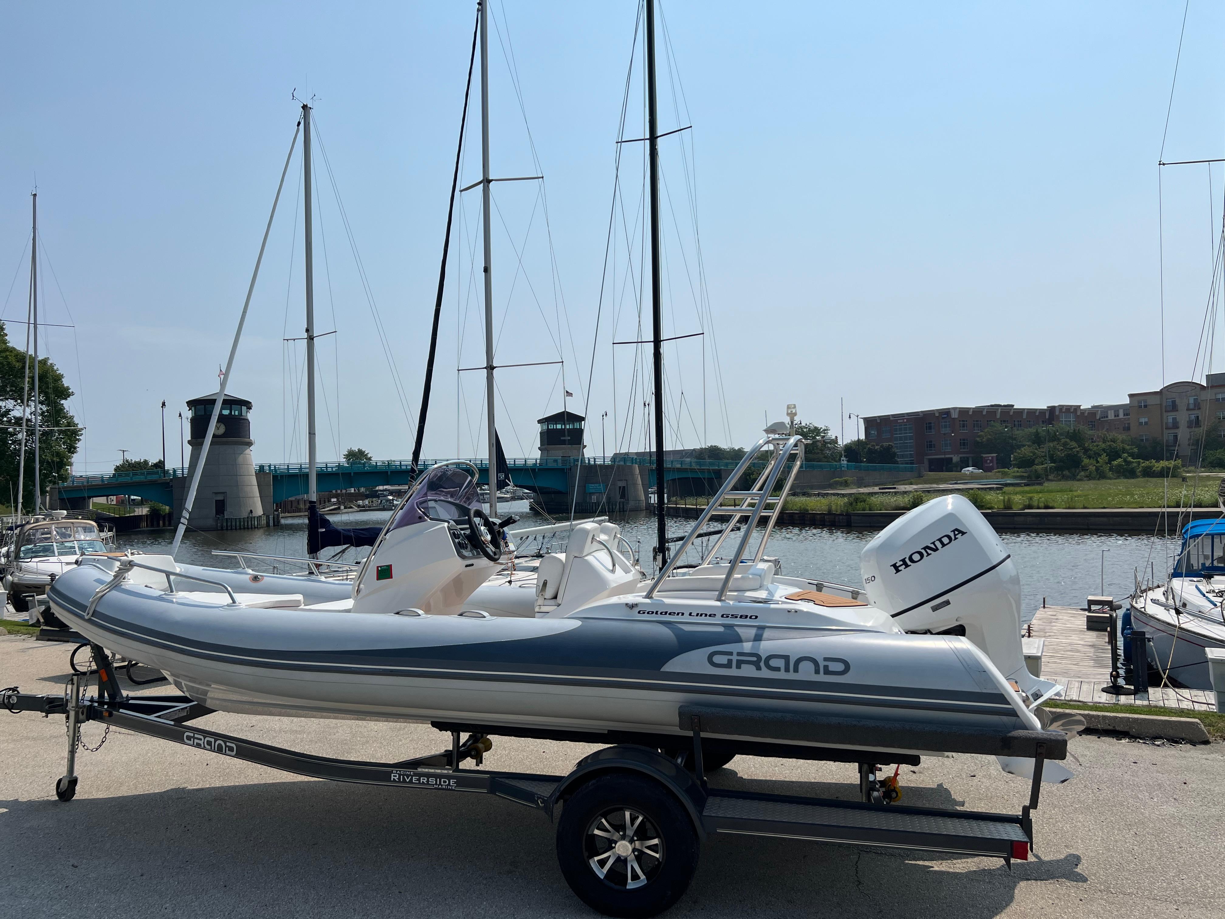 Grand G580 2019 Grand G580HLF boat with Honda engine on trailer by marina.