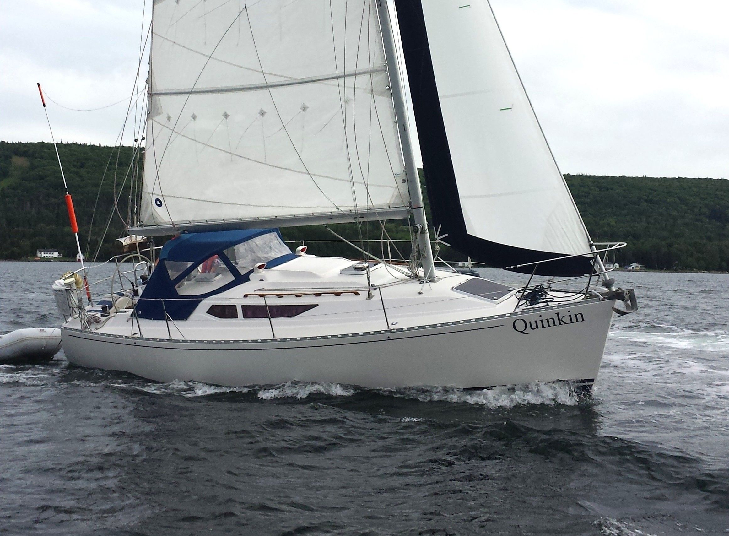 Custom Gilbert 30 Sailing yacht "Quinkin" on water, Custom Gilbert 30, 1988 model, with lush green shoreline.