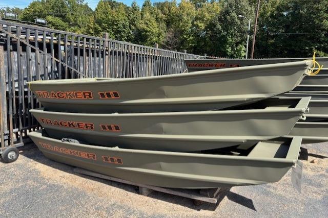 Tracker Grizzly 1036 Utility 2025 Tracker Grizzly 1036 Utility boats stacked outdoors near a fence.