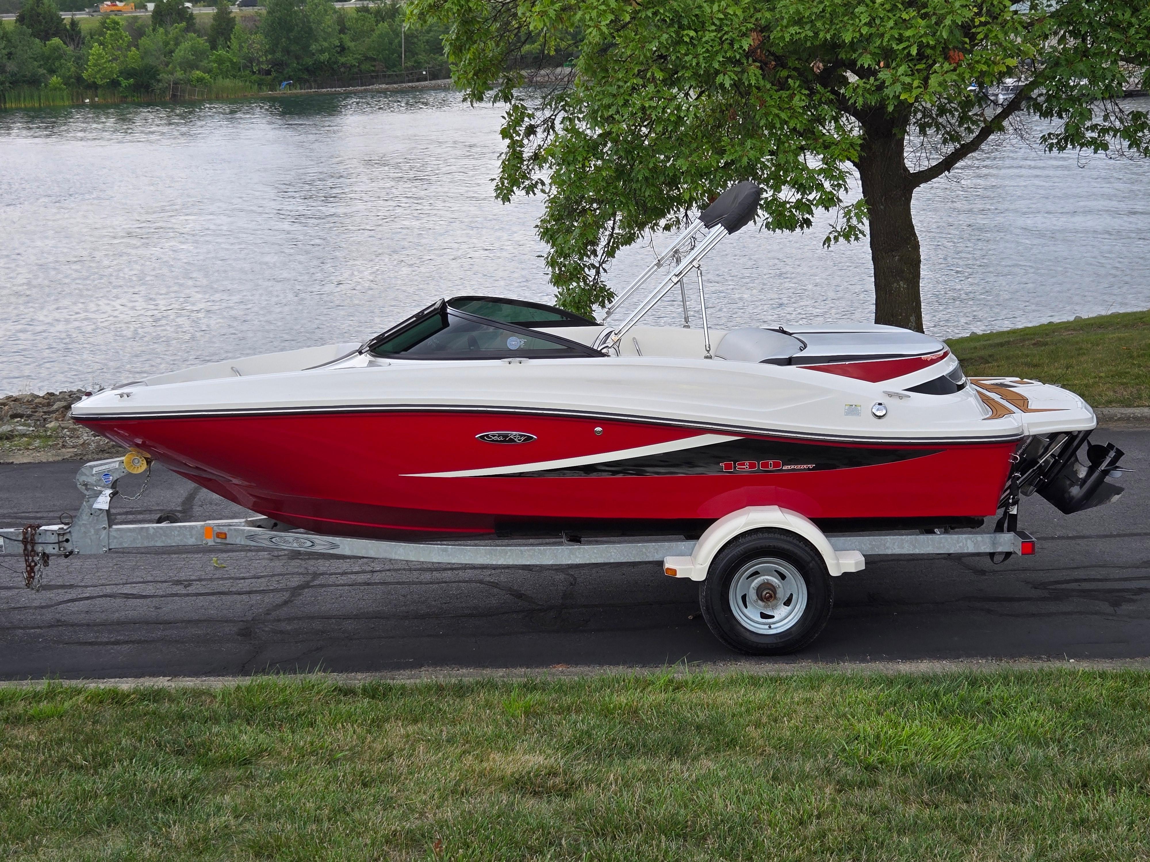 Sea Ray 190 Sport 2012 Sea Ray 190 Sport boat on trailer by a lake, featuring a sleek red design.