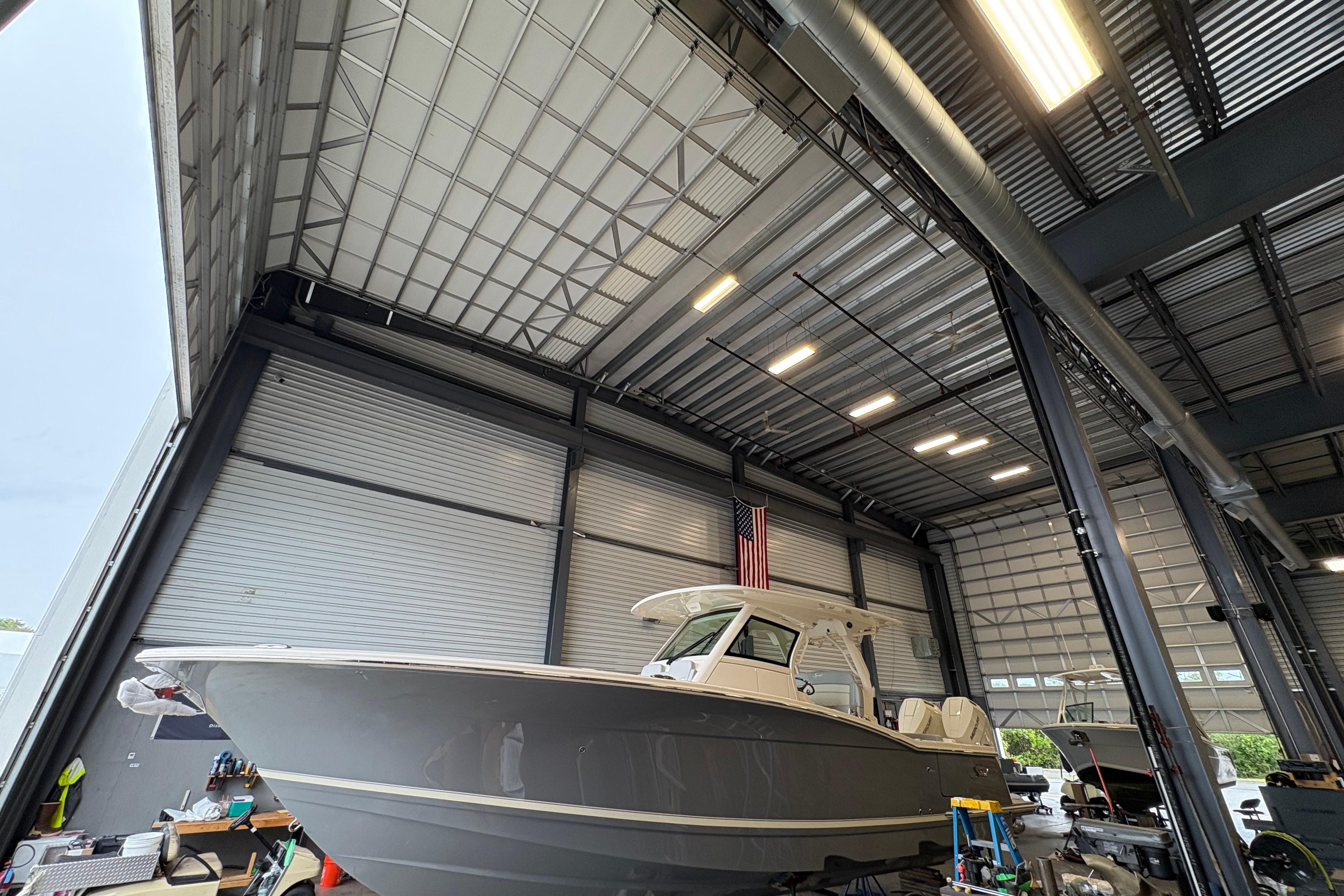 Scout 330 LXF 2026 Scout 330 LXF boat in a spacious indoor storage facility.