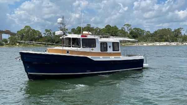 Ranger Tugs R-31S 2019 Ranger Tugs R-31S boat on water, clear sky, lush shoreline background.
