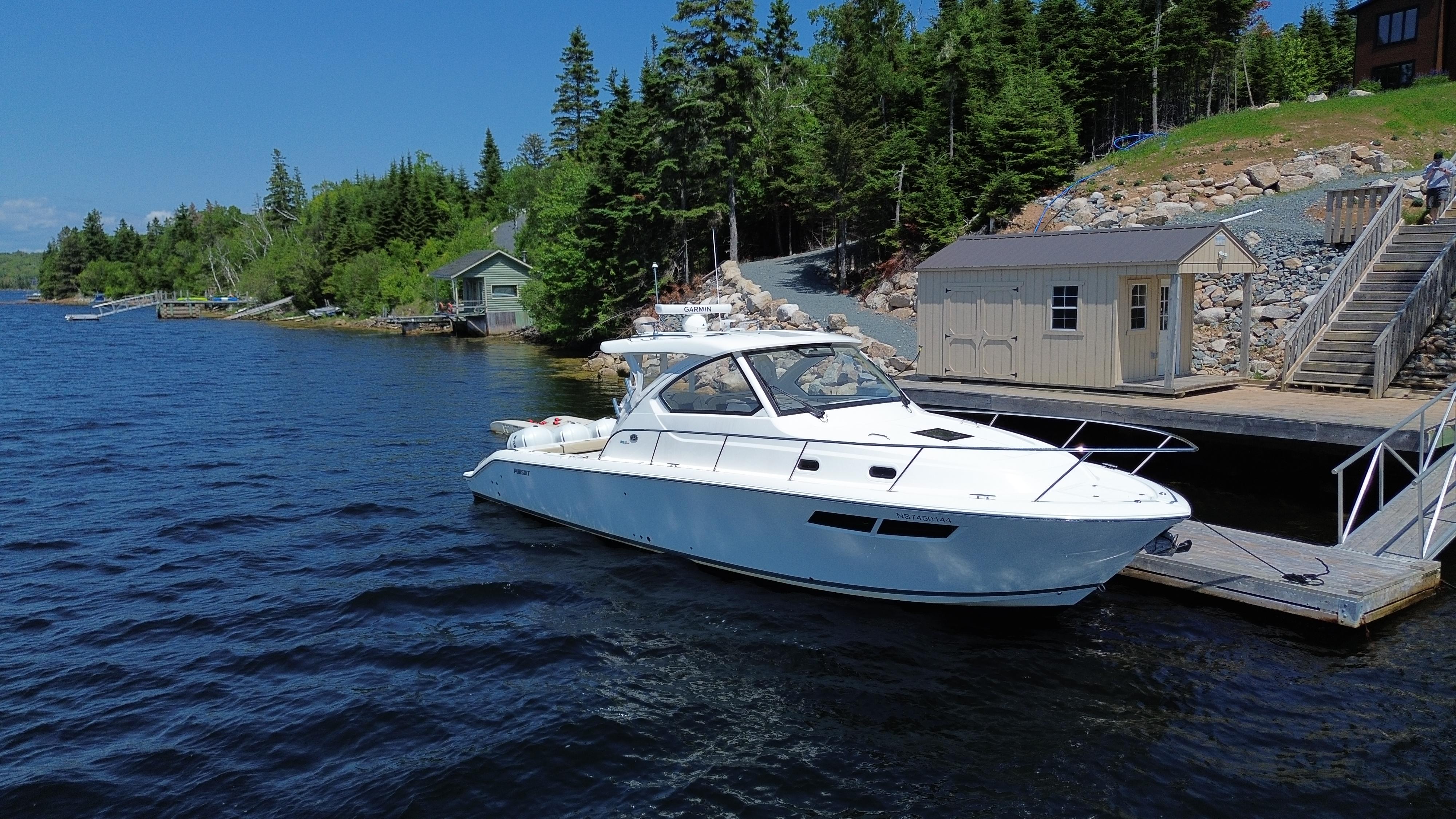Pursuit OS 355 Offshore 2020 Pursuit OS 355 Offshore boat docked by a scenic lakeside cabin.