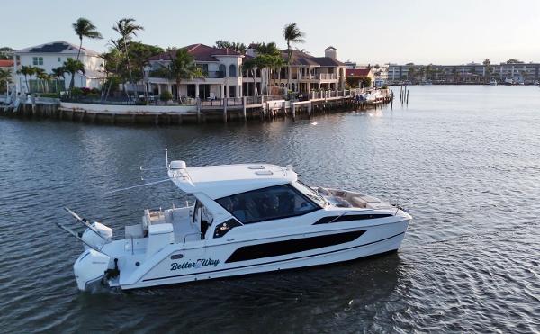 Aquila 36 Sport Aquila 36 Sport 2020 boat cruising near waterfront homes in a serene setting.