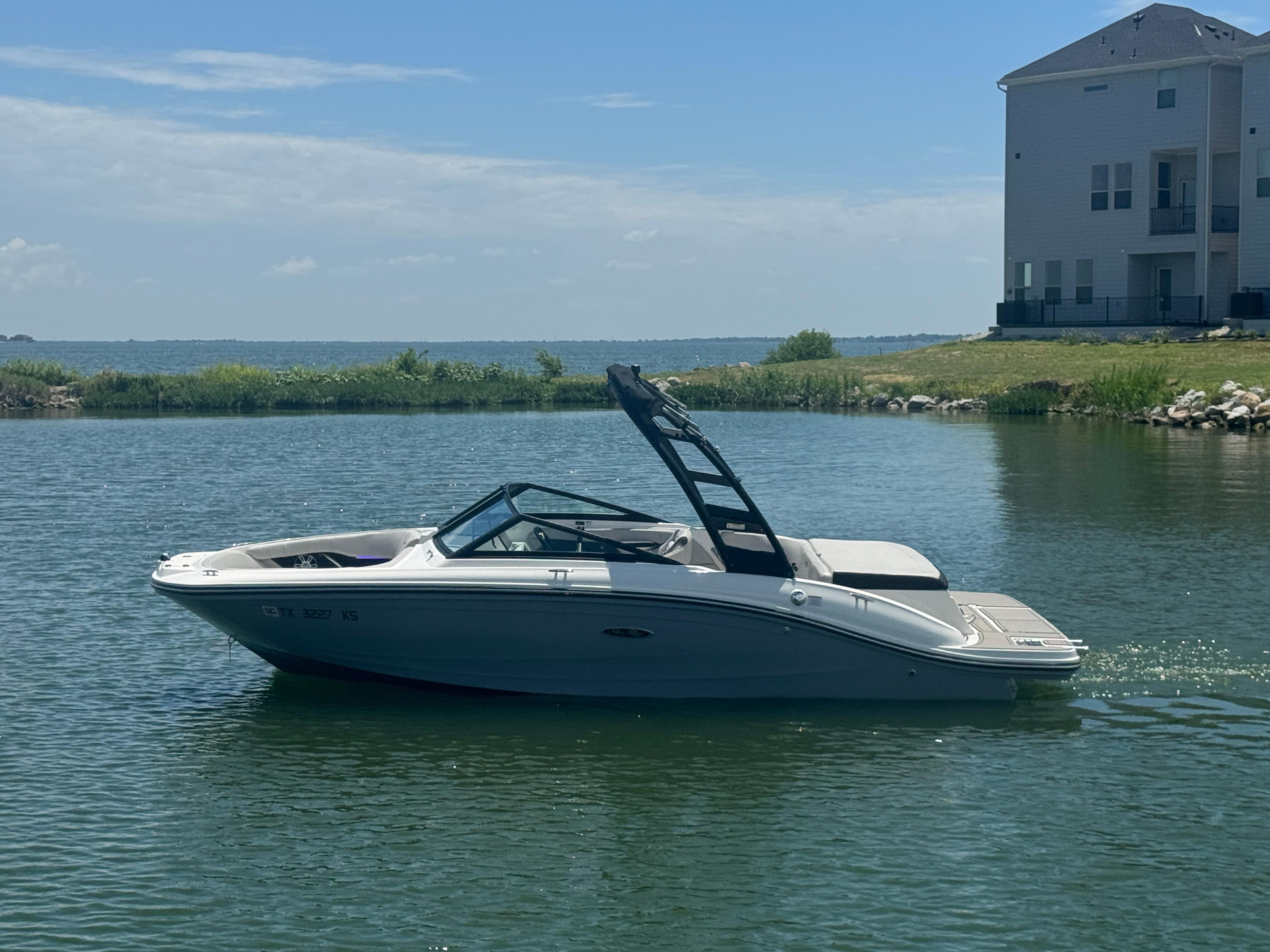 Sea Ray SPX 190 2023 Sea Ray SPX 190 boat on a calm lake near a house.