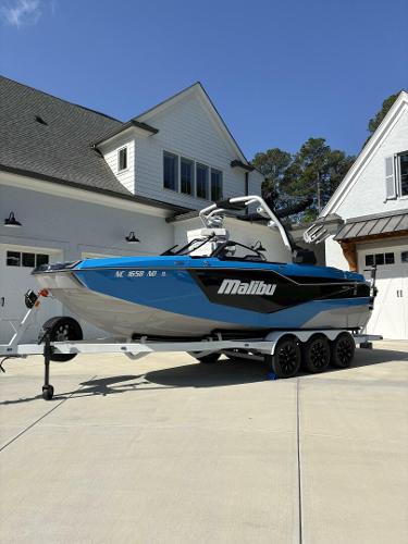 Malibu M242 2024 Malibu M242 boat on trailer in driveway, blue and white design.