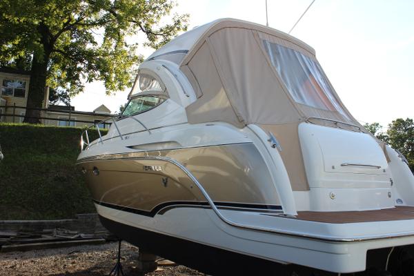 Formula 34 Cruiser 2008 Formula 34 Cruiser boat with beige cover, docked outdoors near trees.