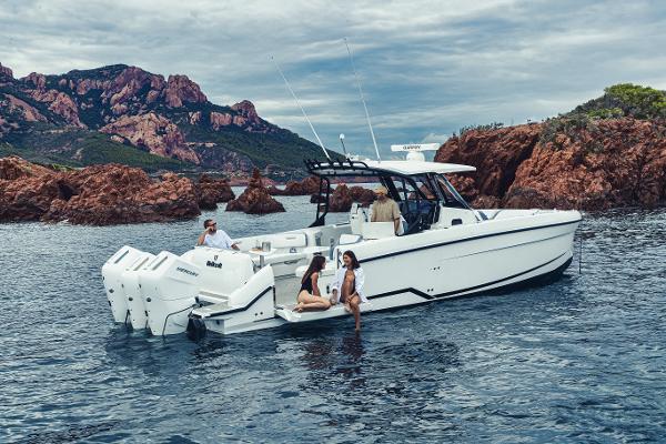 Wellcraft 38 T-Top 2026 Wellcraft 38 T-Top boat with people, cruising near rocky coastline.