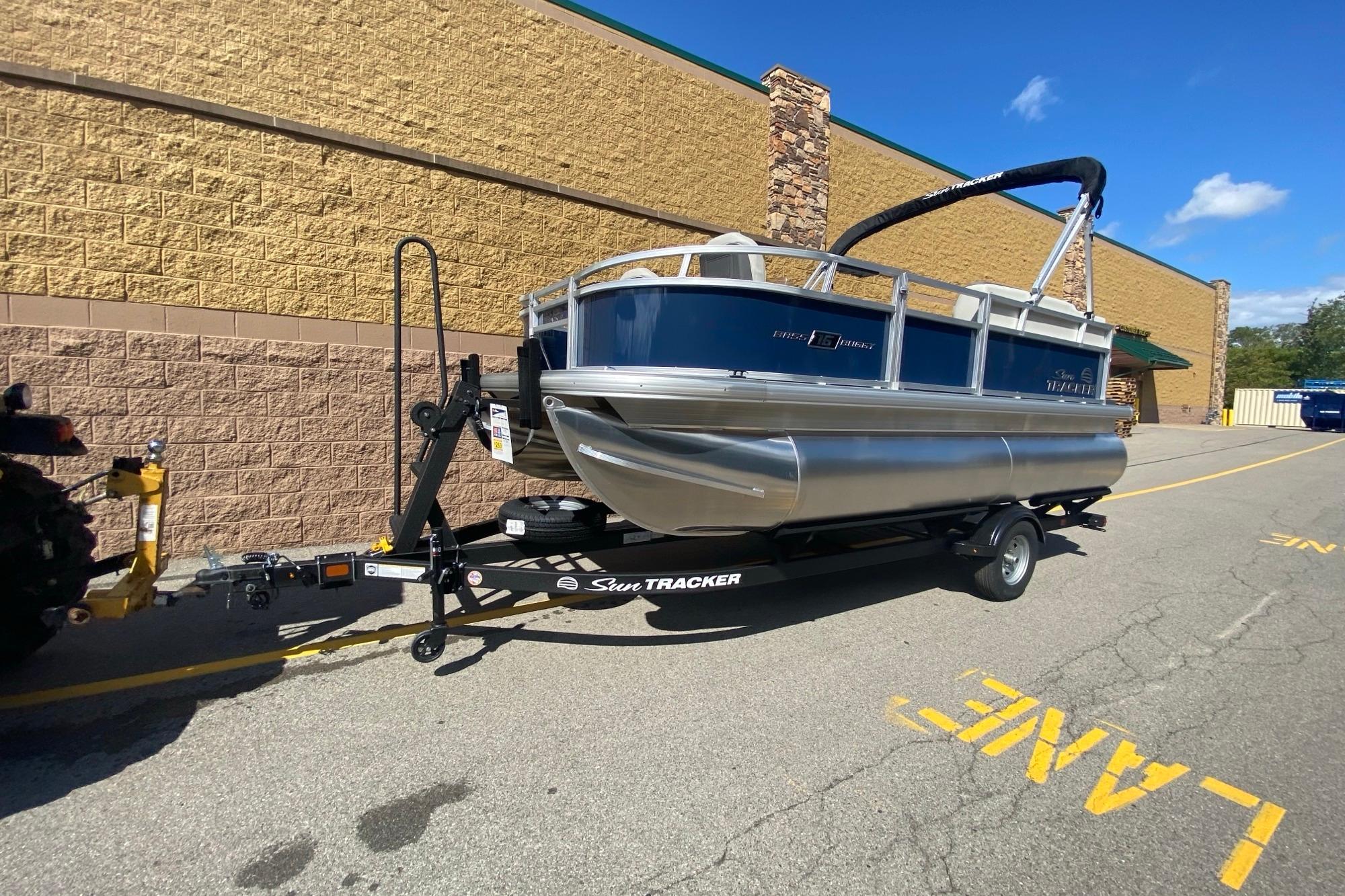 Sun Tracker Bass Buggy 16 XL Select 2026 Sun Tracker Bass Buggy 16 XL Select pontoon boat on trailer, parked outdoors.