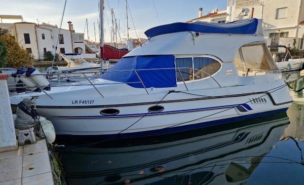Galeon 280 Fly 2002 Galeon 280 Fly yacht docked in a marina, featuring a blue canopy and sleek design.