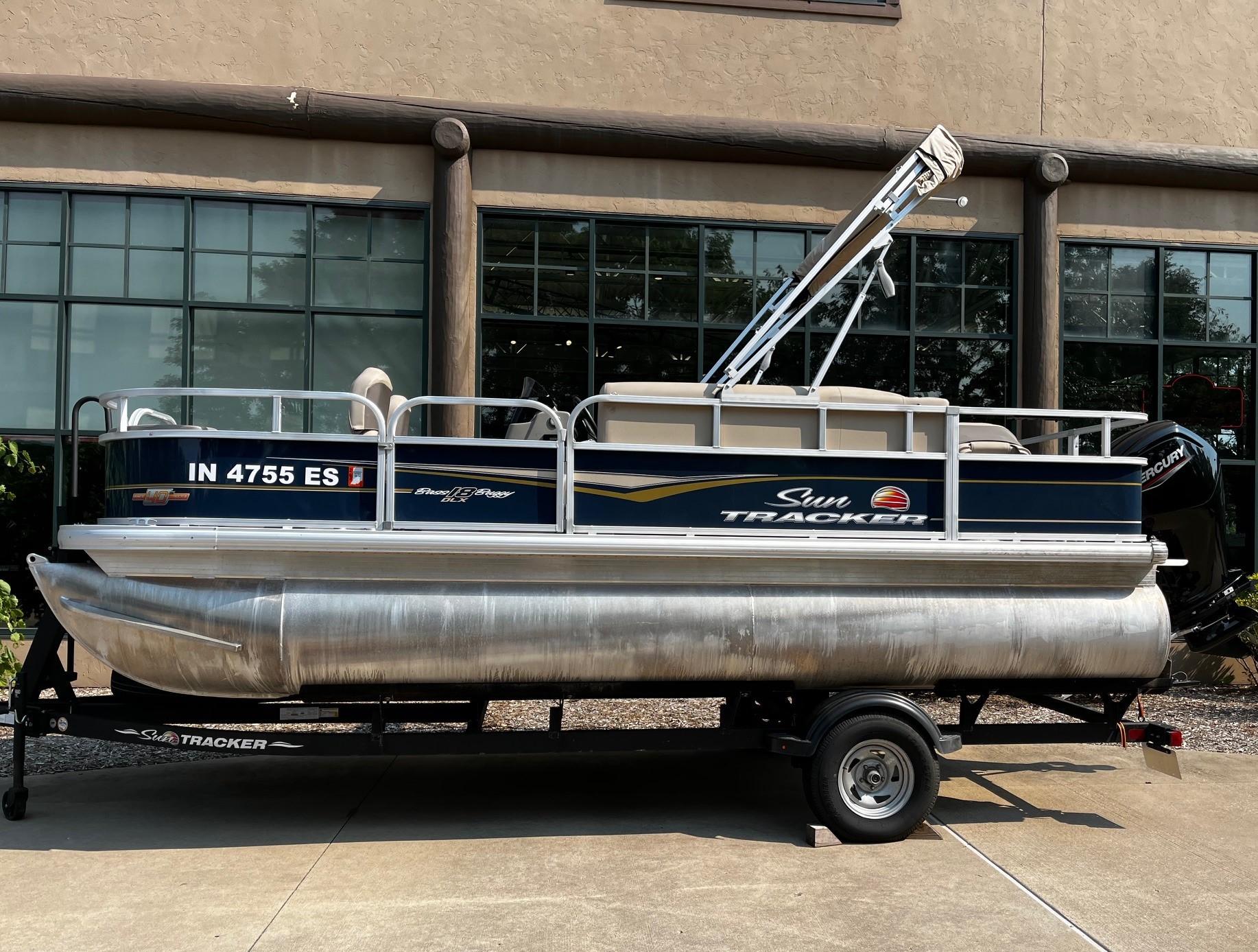 Sun Tracker Bass Buggy 18 DLX 2023 Sun Tracker Bass Buggy 18 DLX pontoon boat on trailer, parked outdoors.