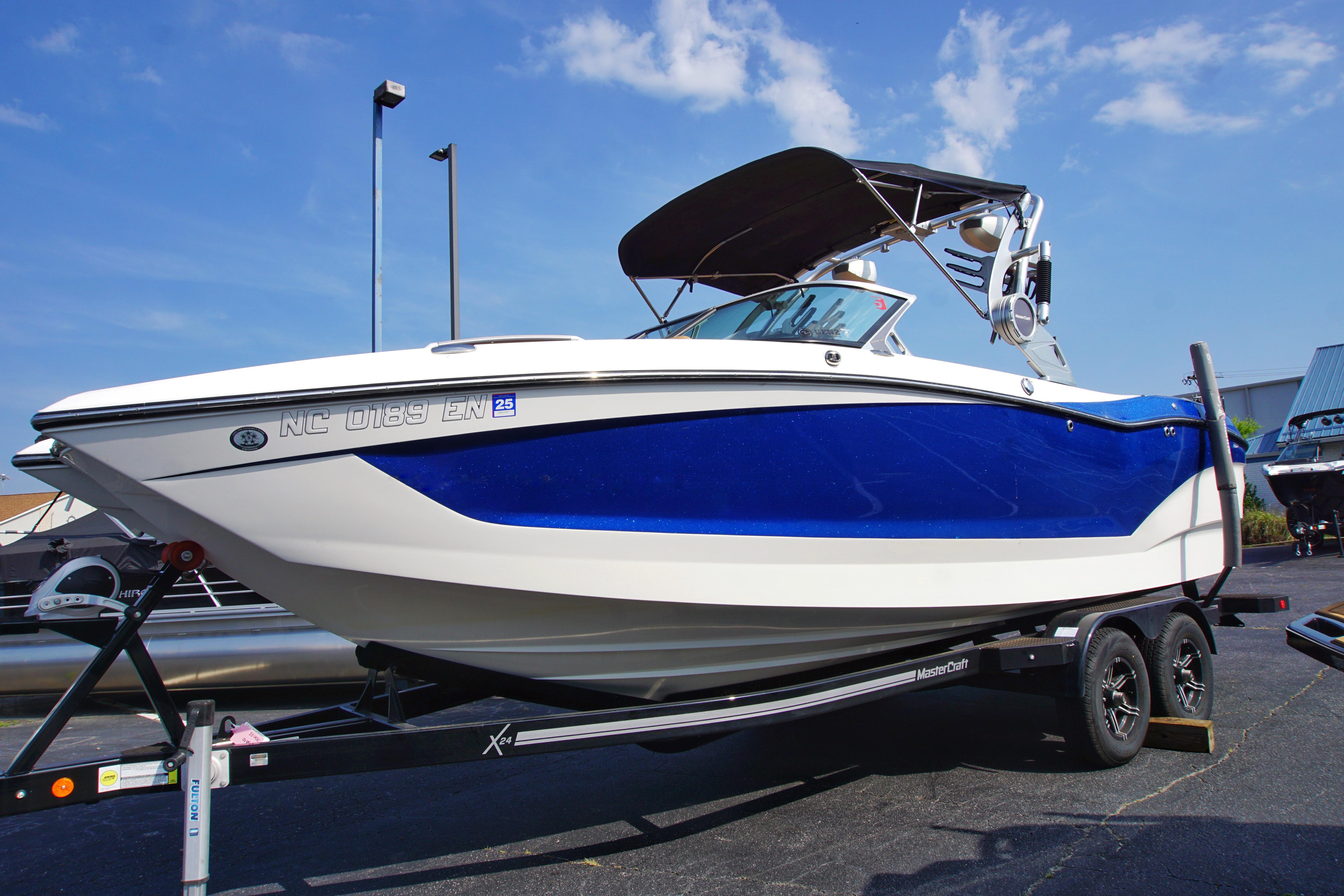 MasterCraft X24 2019 MasterCraft X24 boat on trailer, blue and white design, under clear sky.