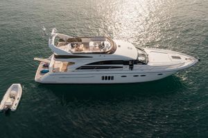 Princess 62 Flybridge Motor Yacht 2008 Princess 62 Flybridge yacht on serene water with small boat nearby.