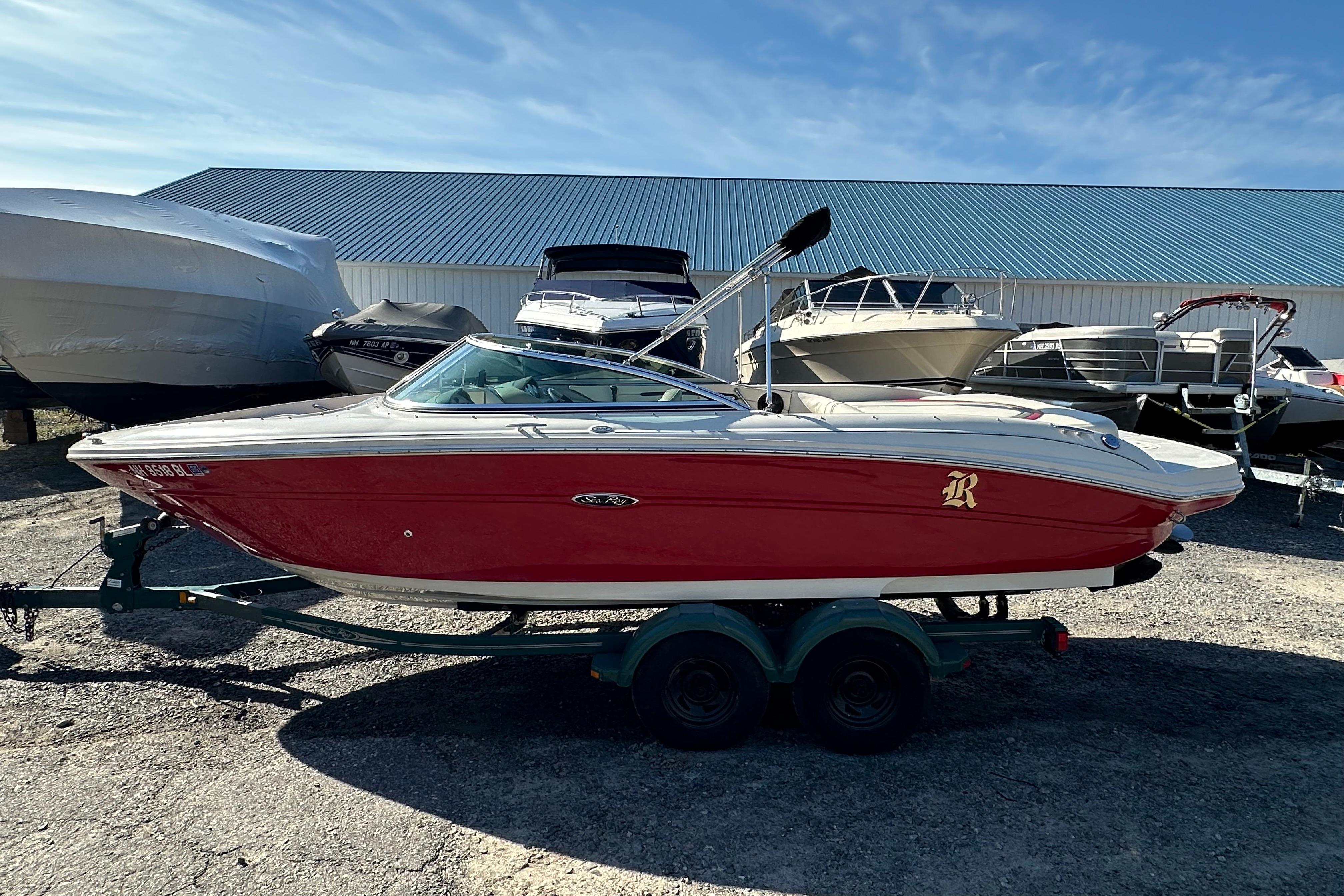 Sea Ray 220 Select 2005 Sea Ray 220 Select boat in red, parked on a trailer, with other boats nearby.