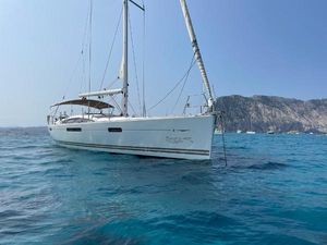 Jeanneau 53 2014 Jeanneau 53 sailboat anchored in clear blue water near rocky coastline.