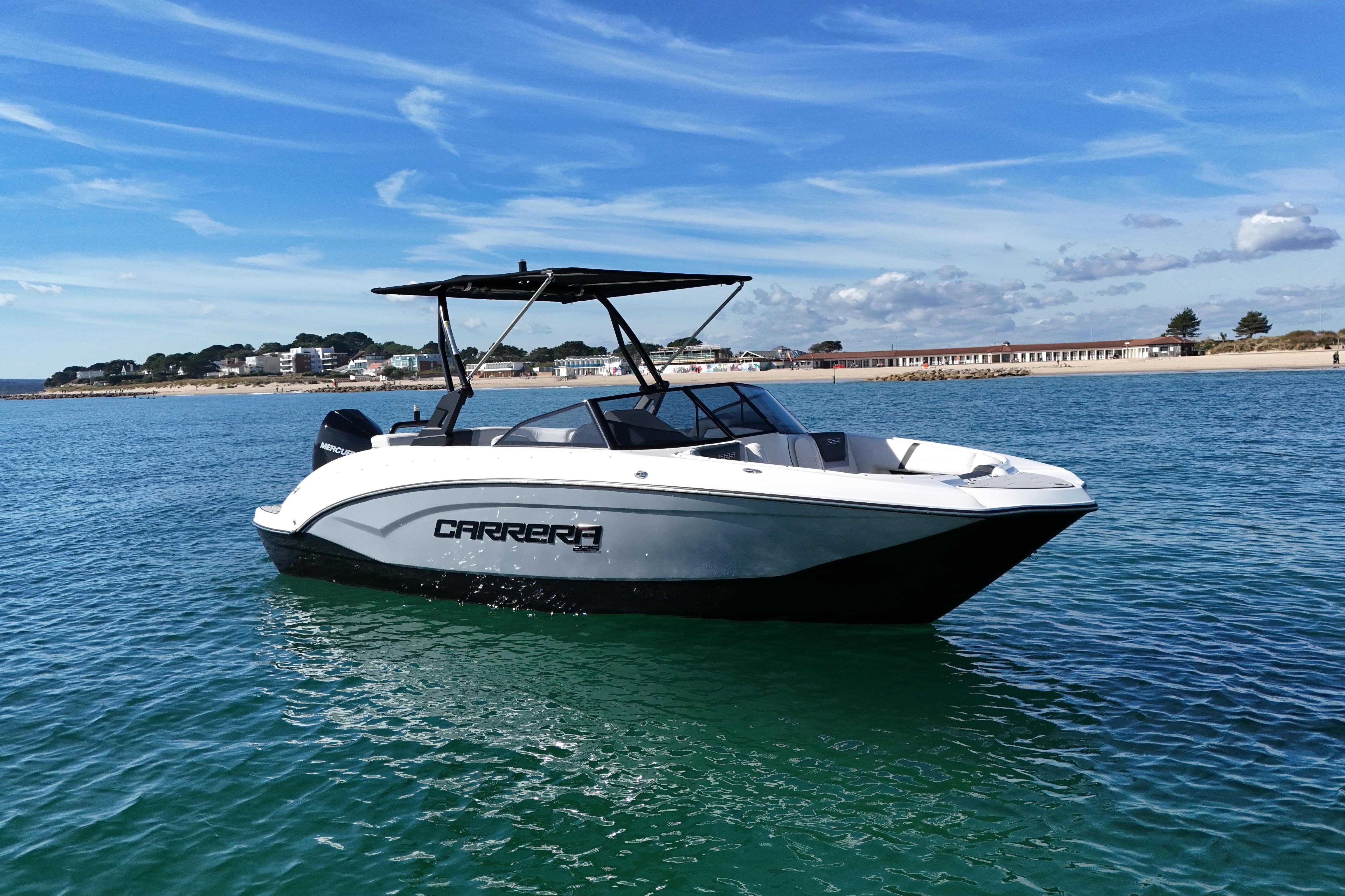 Carrera Boats Carrera 225 2026 Carrera 225 boat on clear blue water near a scenic coastline.
