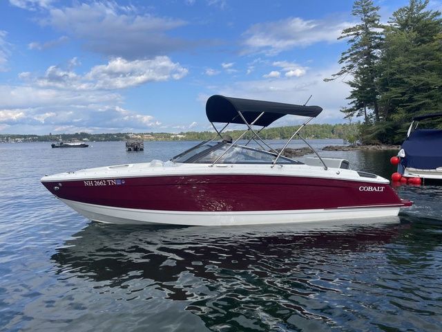 Cobalt R4 2025 Cobalt R4 boat with canopy on a serene lake under a blue sky.