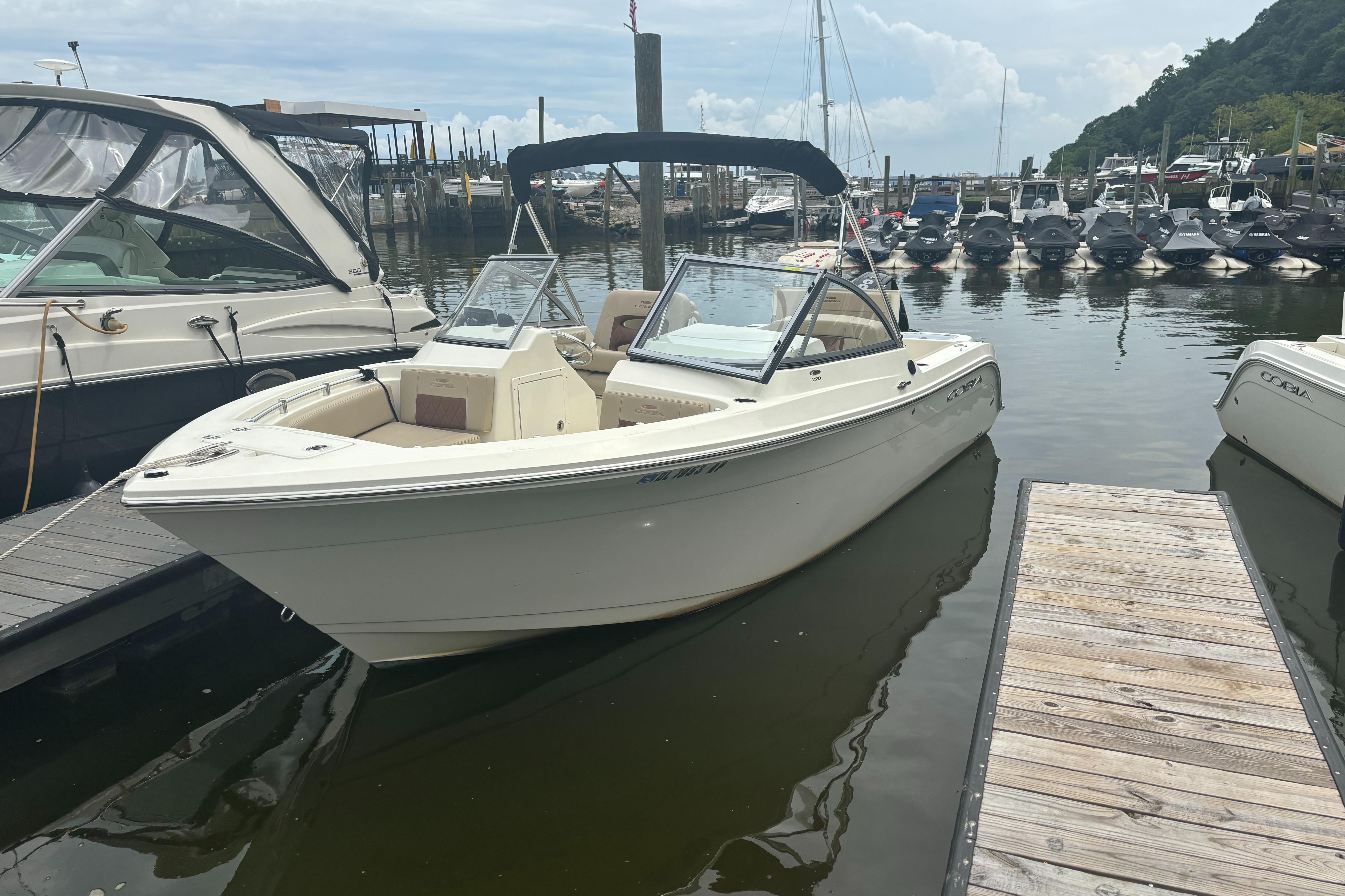 Cobia 220 Dual Console 2024 Cobia 220 Dual Console boat docked at a marina, surrounded by other vessels.