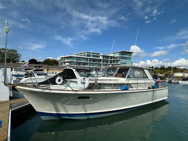 Chris-Craft Commander 1969 Chris-Craft Commander boat docked at a marina with modern buildings in the background.