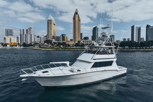 Hatteras 58 Convertible 1990 Hatteras 58 Convertible yacht cruising near city skyline under cloudy sky.