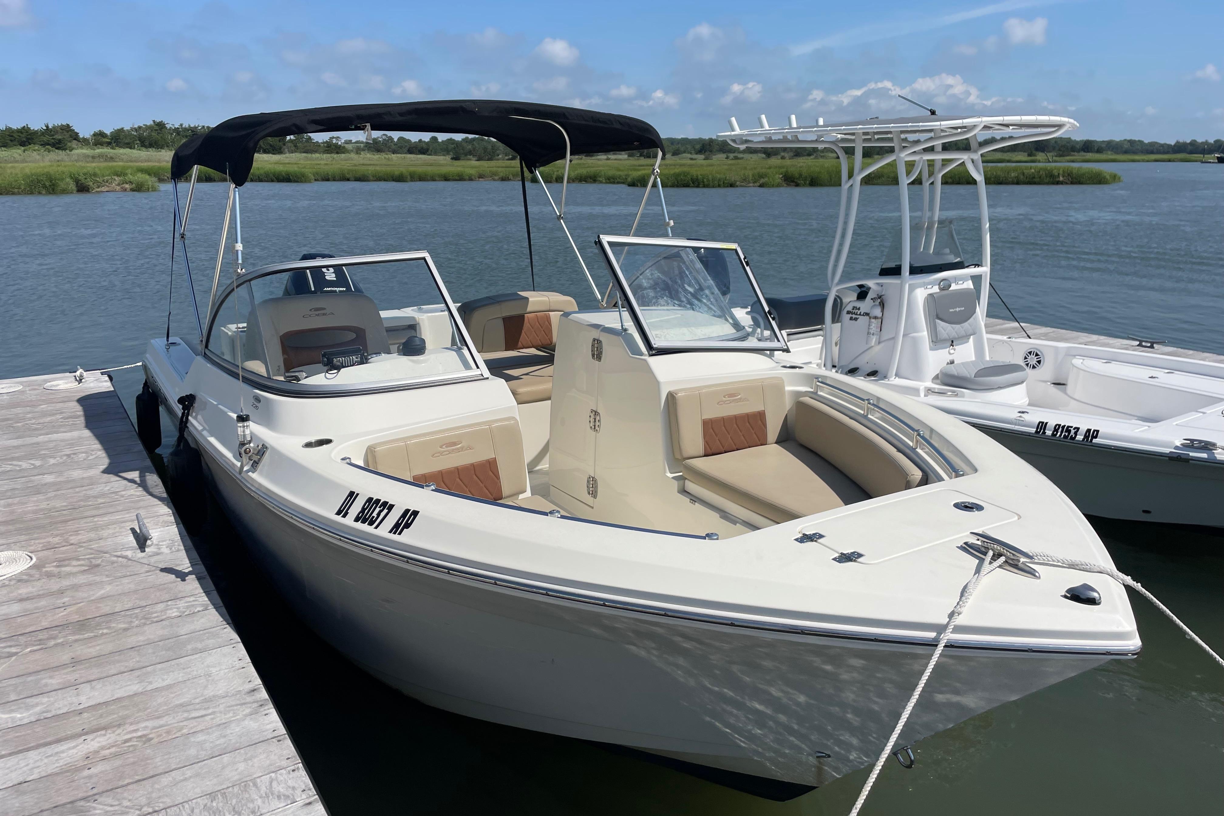 Cobia 220 Dual Console 2024 Cobia 220 Dual Console boat docked by the water on a sunny day.