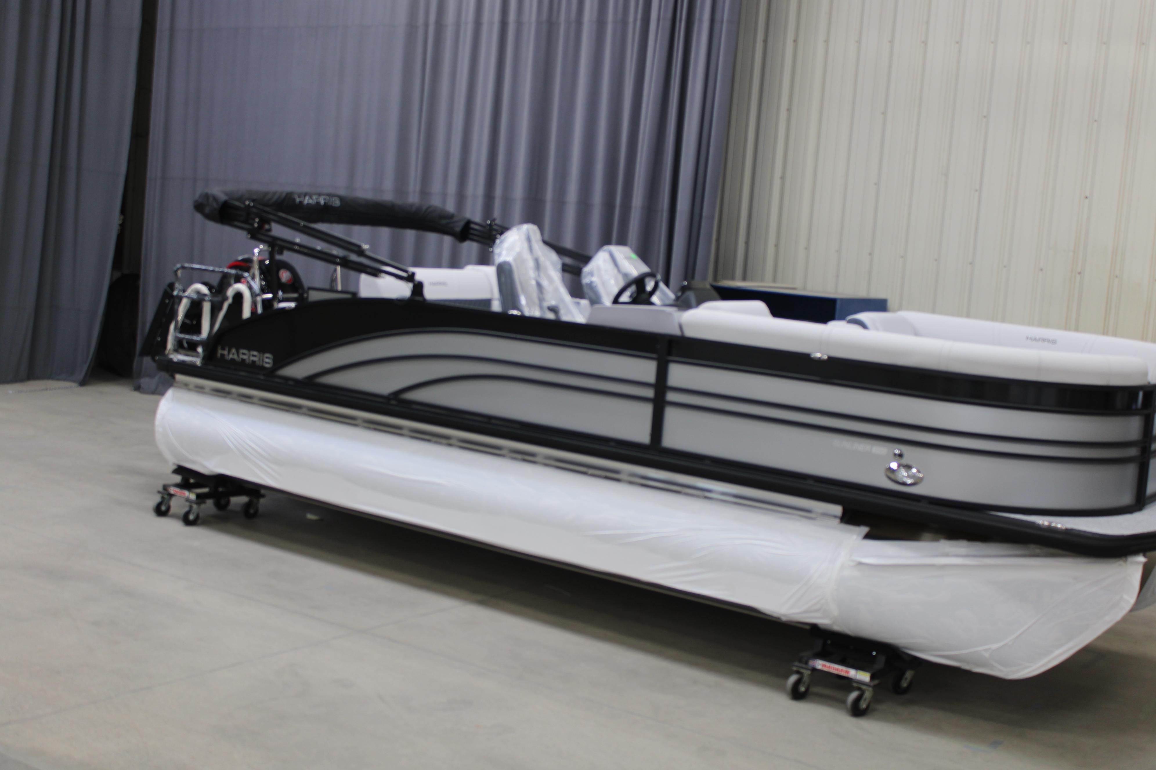Harris Sunliner 230 2025 Harris Sunliner 230 pontoon boat in showroom, sleek design, black and white color scheme.