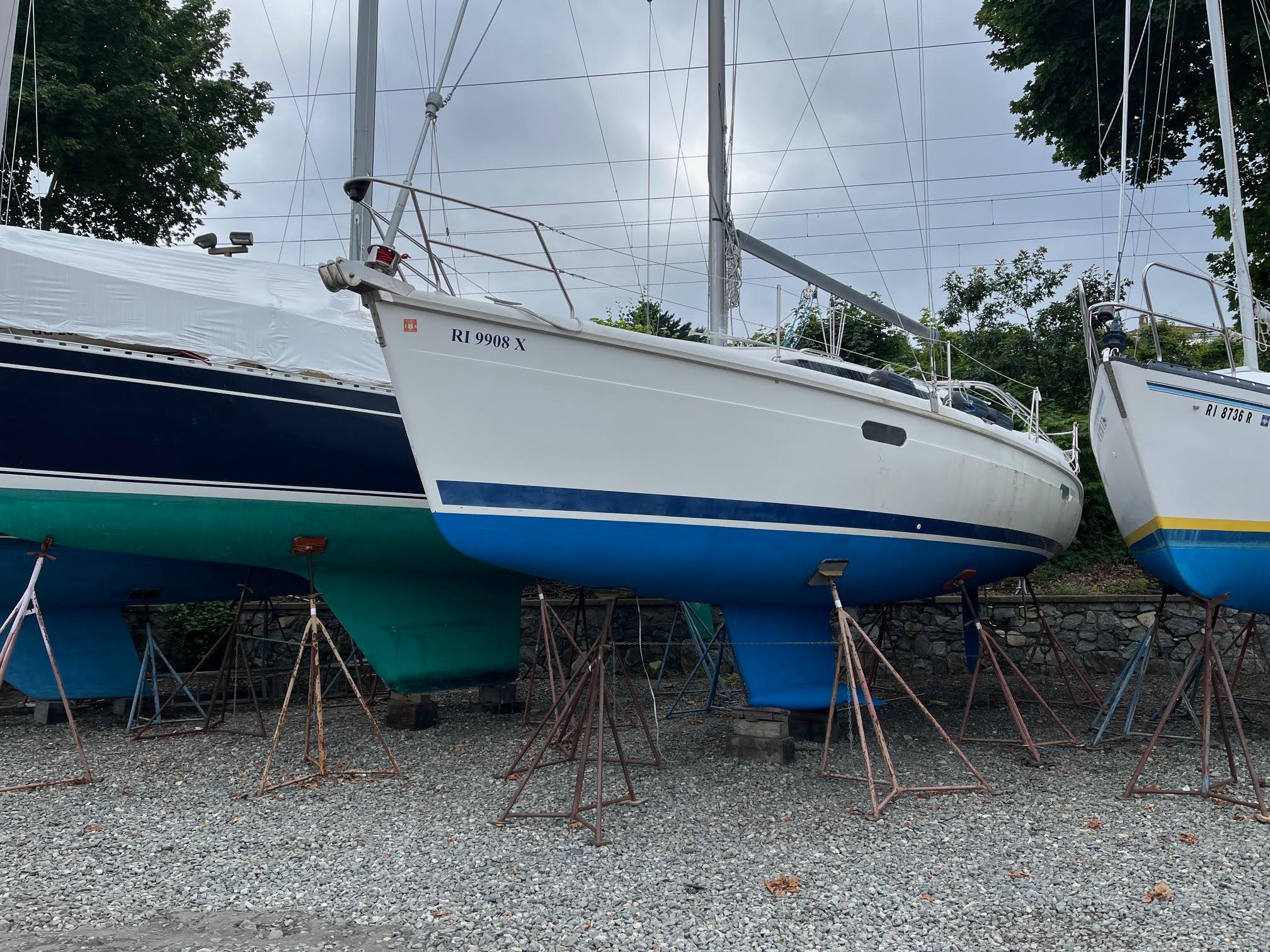Hunter 336 1995 Hunter 336 sailboat on stands, white hull with blue bottom, overcast sky.
