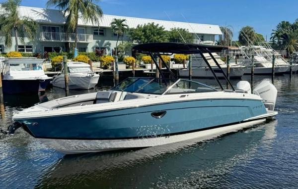 Cobalt R8 Outboard 2023 Cobalt R8 Outboard boat docked in a marina, surrounded by palm trees and other boats.