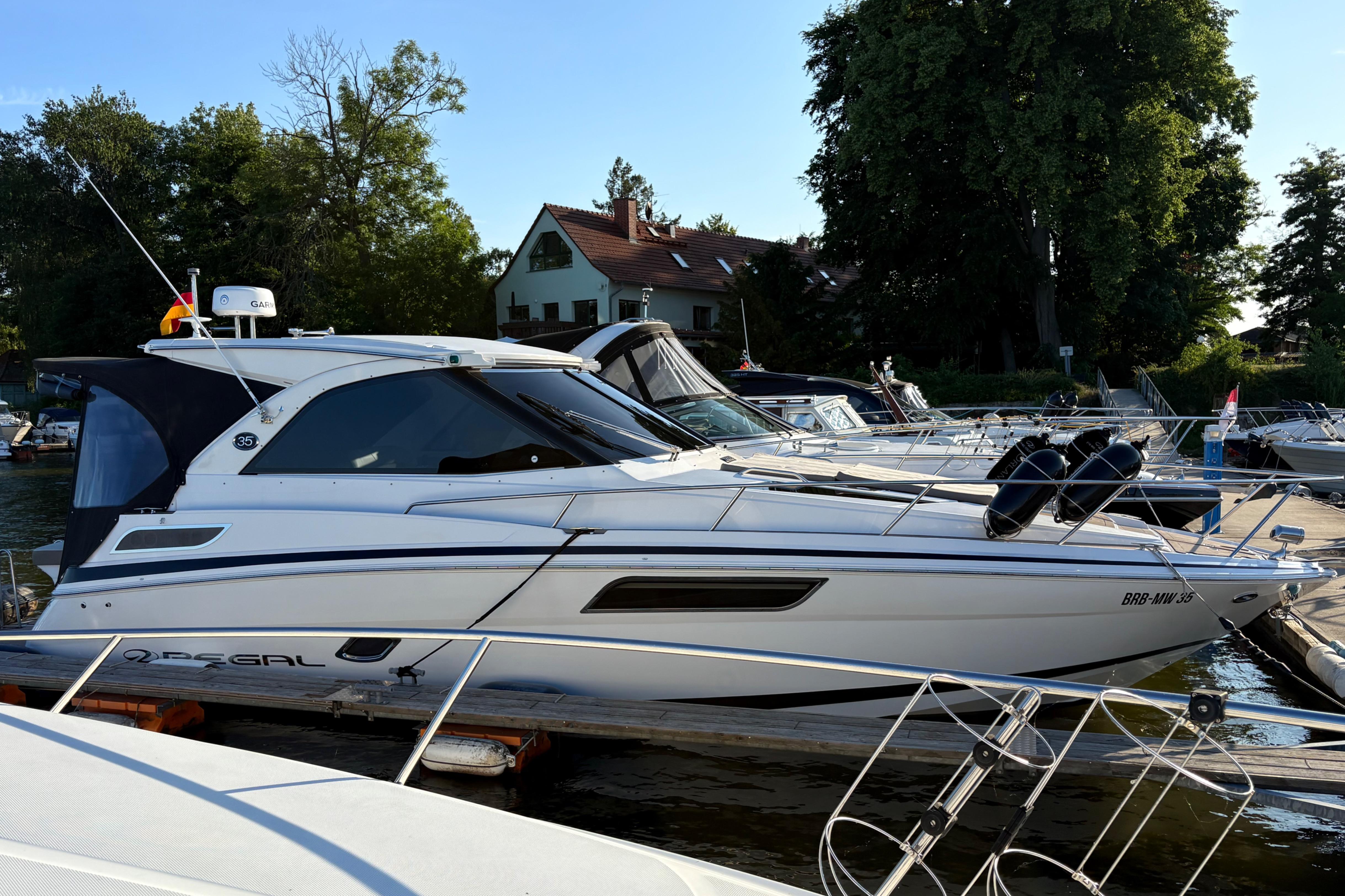 Regal 35 Sport Coupe 2017 Regal 35 Sport Coupe yacht docked at marina, surrounded by trees and buildings.