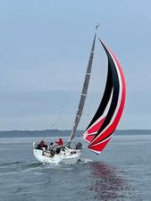 Hanse 315 2018 Hanse 315 sailboat with vibrant red and black spinnaker on calm water.