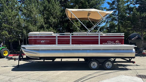 Sun Tracker Party Barge 22 DLX 2025 Sun Tracker Party Barge 22 DLX pontoon boat on trailer, parked outdoors.