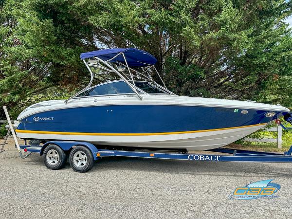 Cobalt 222 2007 Cobalt 222 boat on trailer, blue and white design, parked near trees.