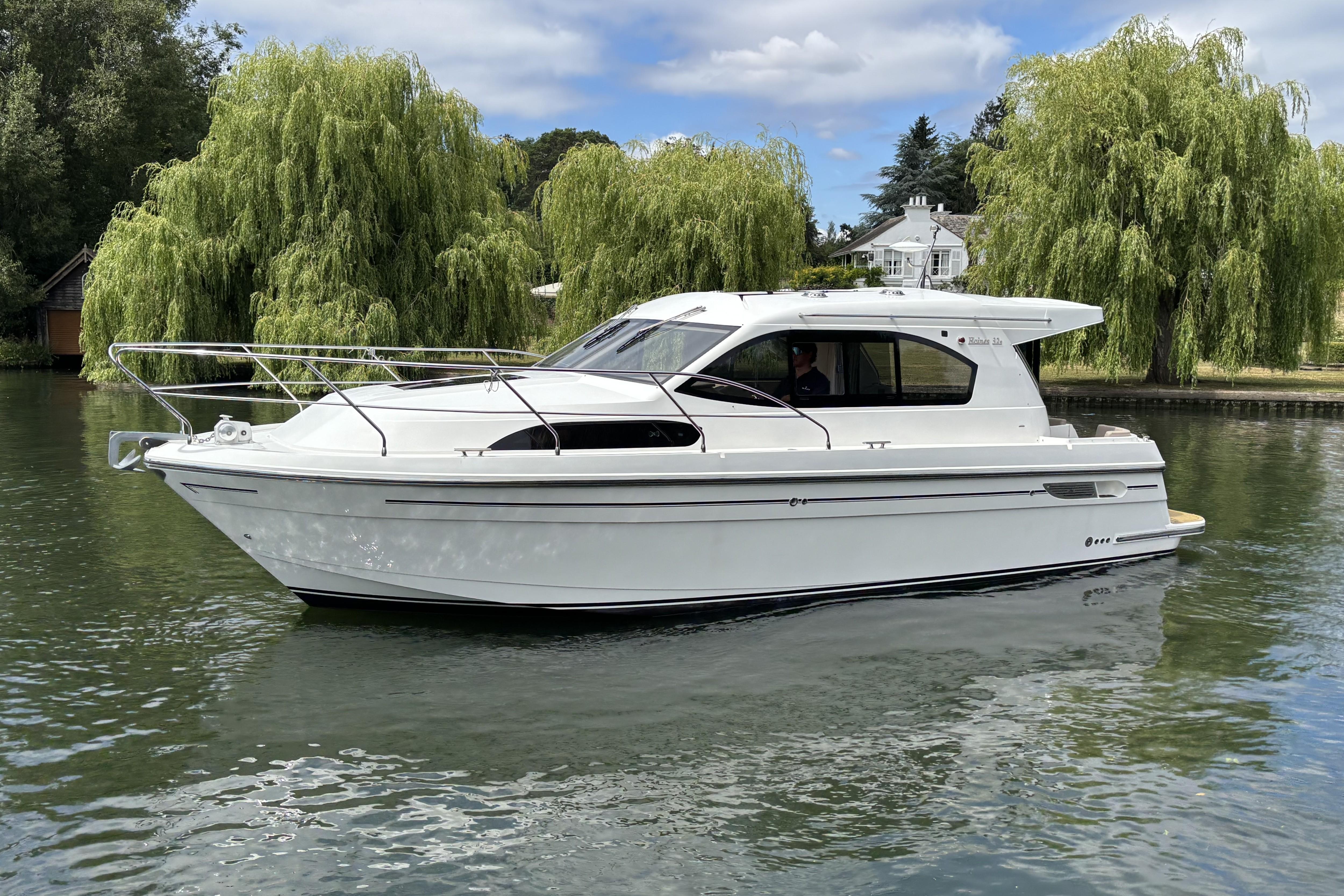 Haines 32 SEDAN 2016 Haines 32 Sedan boat on a serene river with lush greenery.