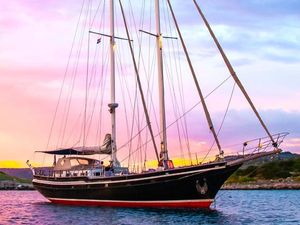 Custom 19m Steel Staysail Schooner 19m Custom Steel Staysail Schooner, 1984, sailing at sunset with vibrant sky backdrop.
