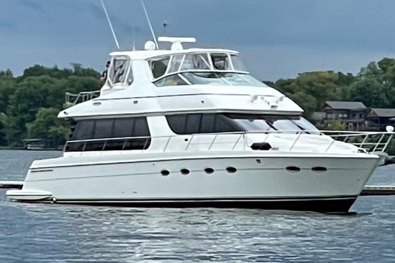 Carver 570 Voyager Pilothouse 2004 Carver 570 Voyager Pilothouse yacht on a serene lake with lush greenery.