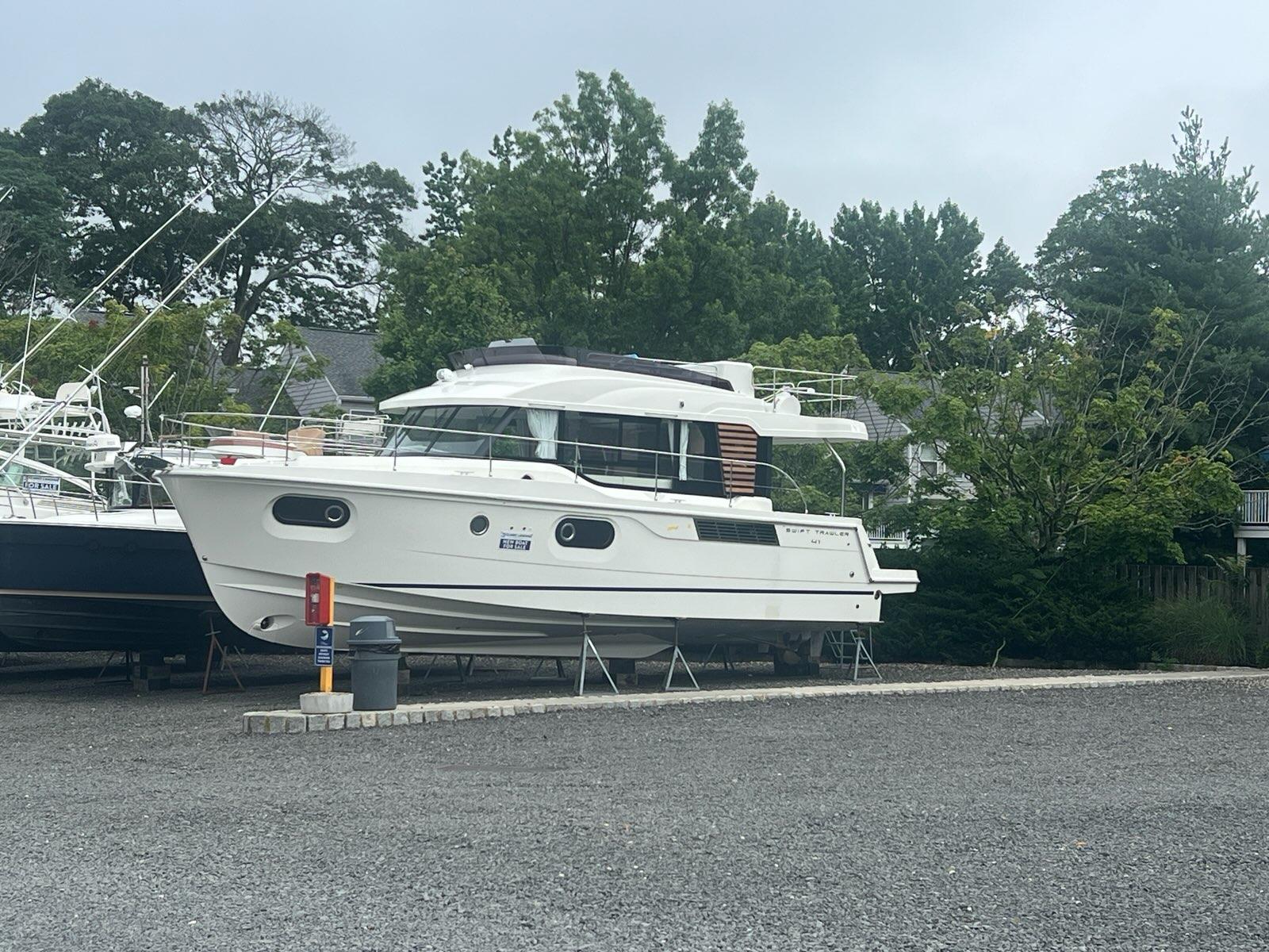 Beneteau Swift Trawler 41 Fly 2026 Beneteau Swift Trawler 41 Fly on land, surrounded by trees and other boats.