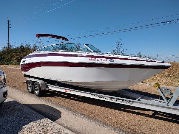 Crownline 270 BR 2006 Crownline 270 BR boat on trailer, parked on roadside under clear blue sky.