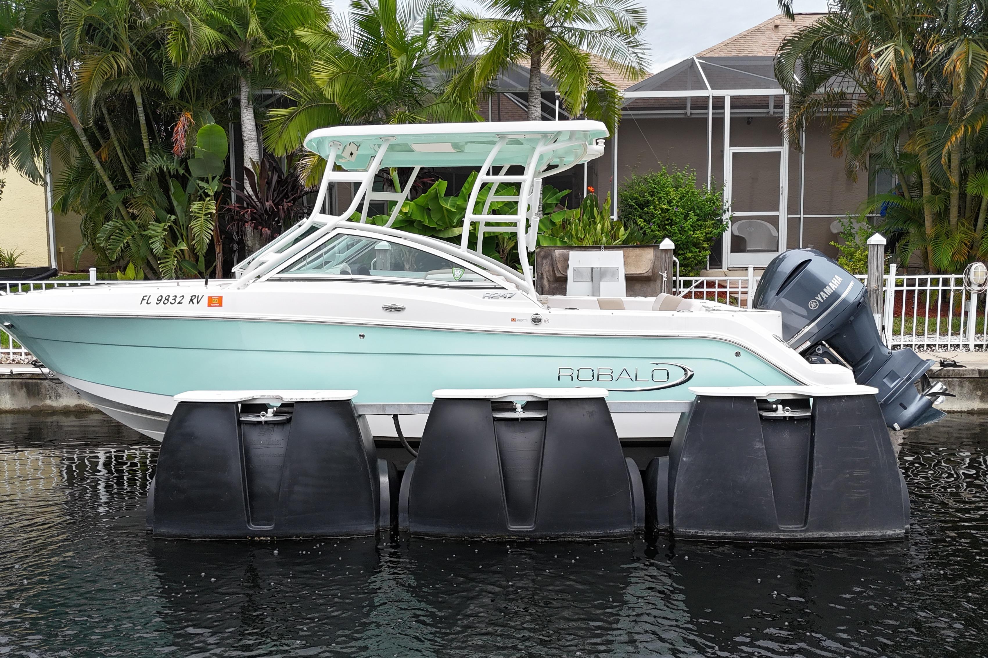 Robalo R247 Dual Console 2019 Robalo R247 Dual Console boat docked on water, surrounded by lush greenery.