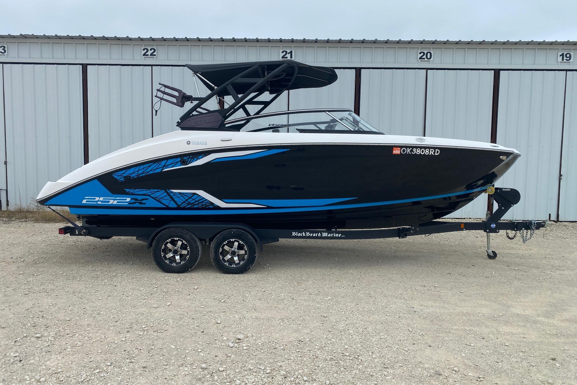Yamaha Boats 252XE 2021 Yamaha Boats 252XE on trailer, black and blue design, parked outside storage units.