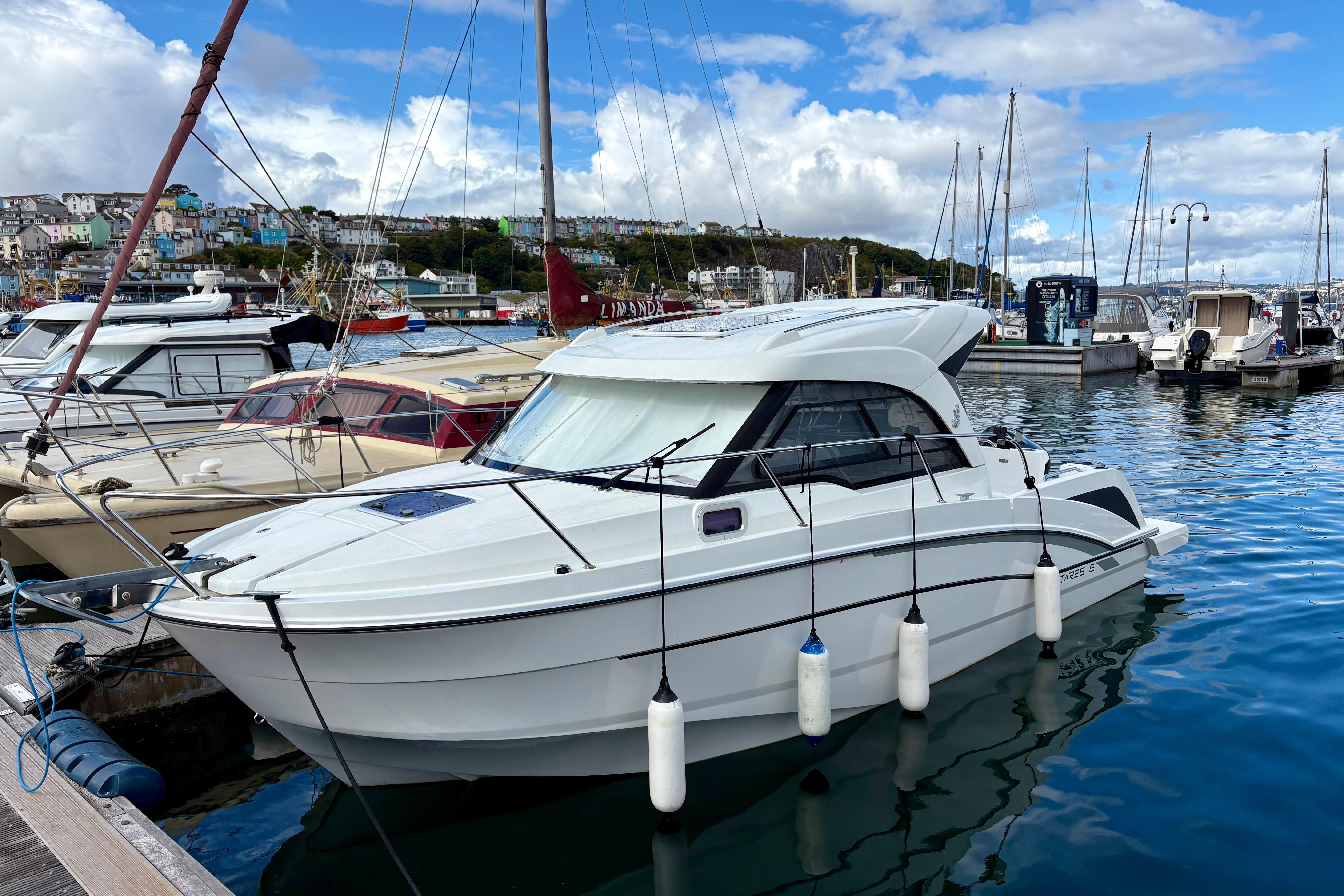 Beneteau Antares 8 2019 Beneteau Antares 8 docked in a scenic marina with sailboats.