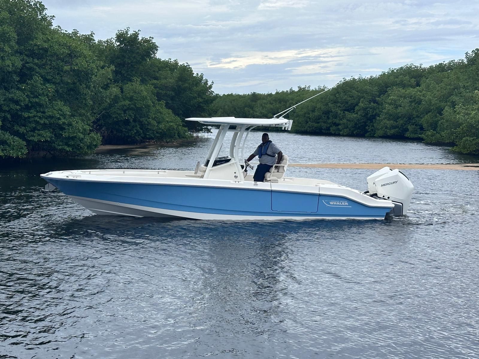 Boston Whaler 280 Dauntless 2026 Boston Whaler 280 Dauntless boat cruising on a calm river near lush greenery.