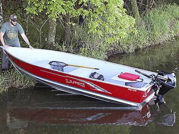 Lund WC 14 Tiller 2024 Lund WC-14 Tiller boat in water near a forested shoreline.