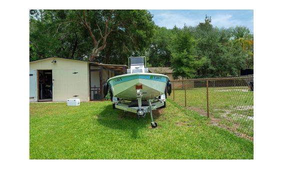 Avid 21 Fusion Avid 21 Fusion 2022 boat on trailer in grassy yard near shed.