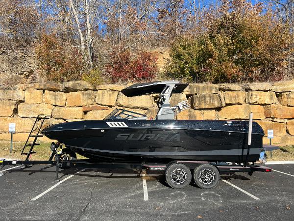 Supra SE 2022 Supra SE boat on trailer, parked outdoors with autumn foliage background.