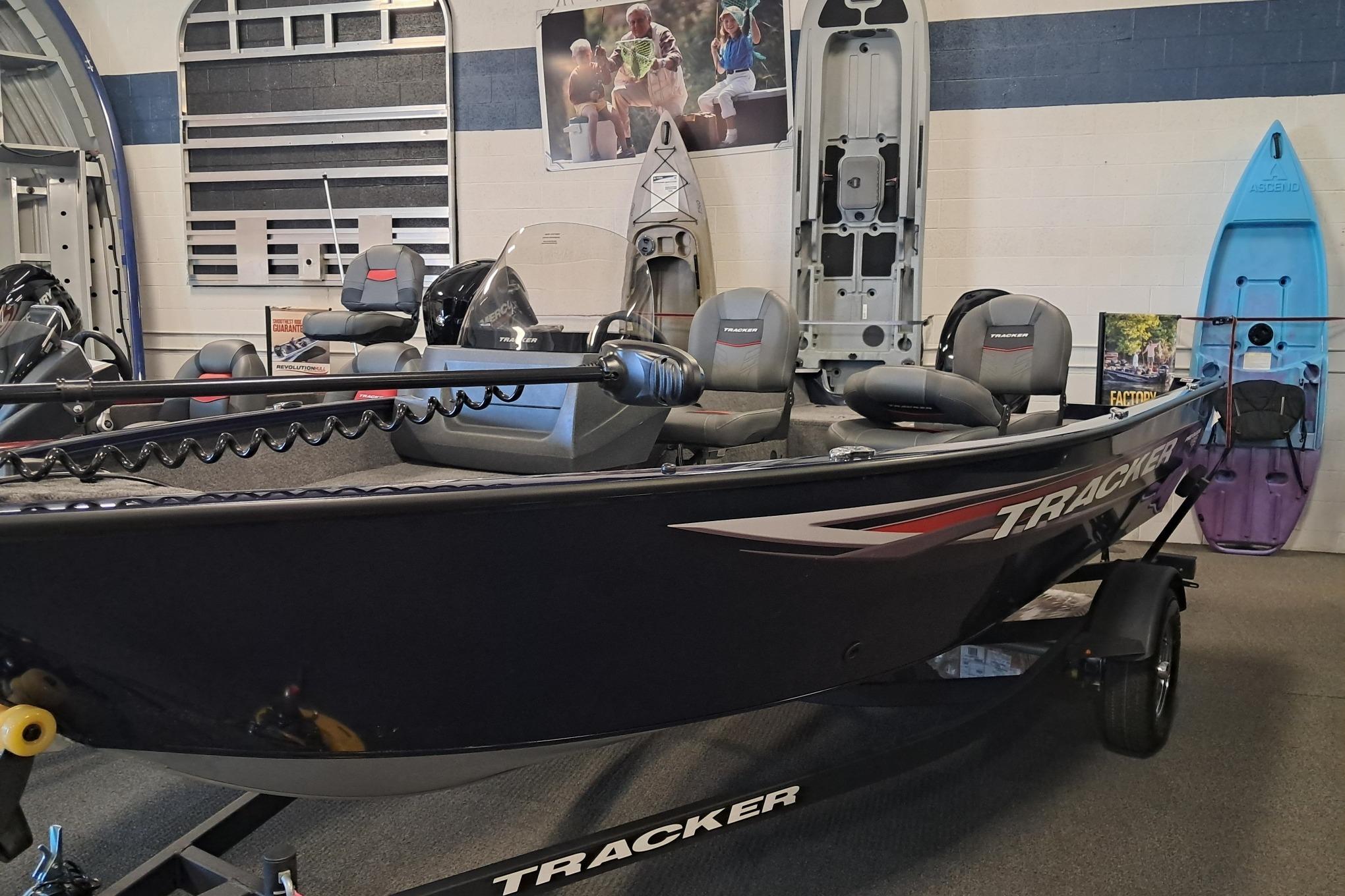 Tracker Pro Guide V-16 SC 2025 Tracker Pro Guide V-16 SC boat displayed in showroom with kayaks and accessories.