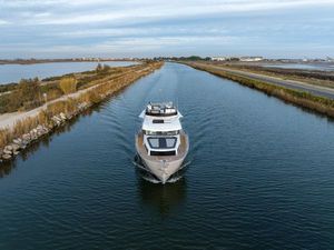 Delphia D12 Fly 2025 Delphia D12 Fly yacht cruising on a serene canal, surrounded by lush greenery.