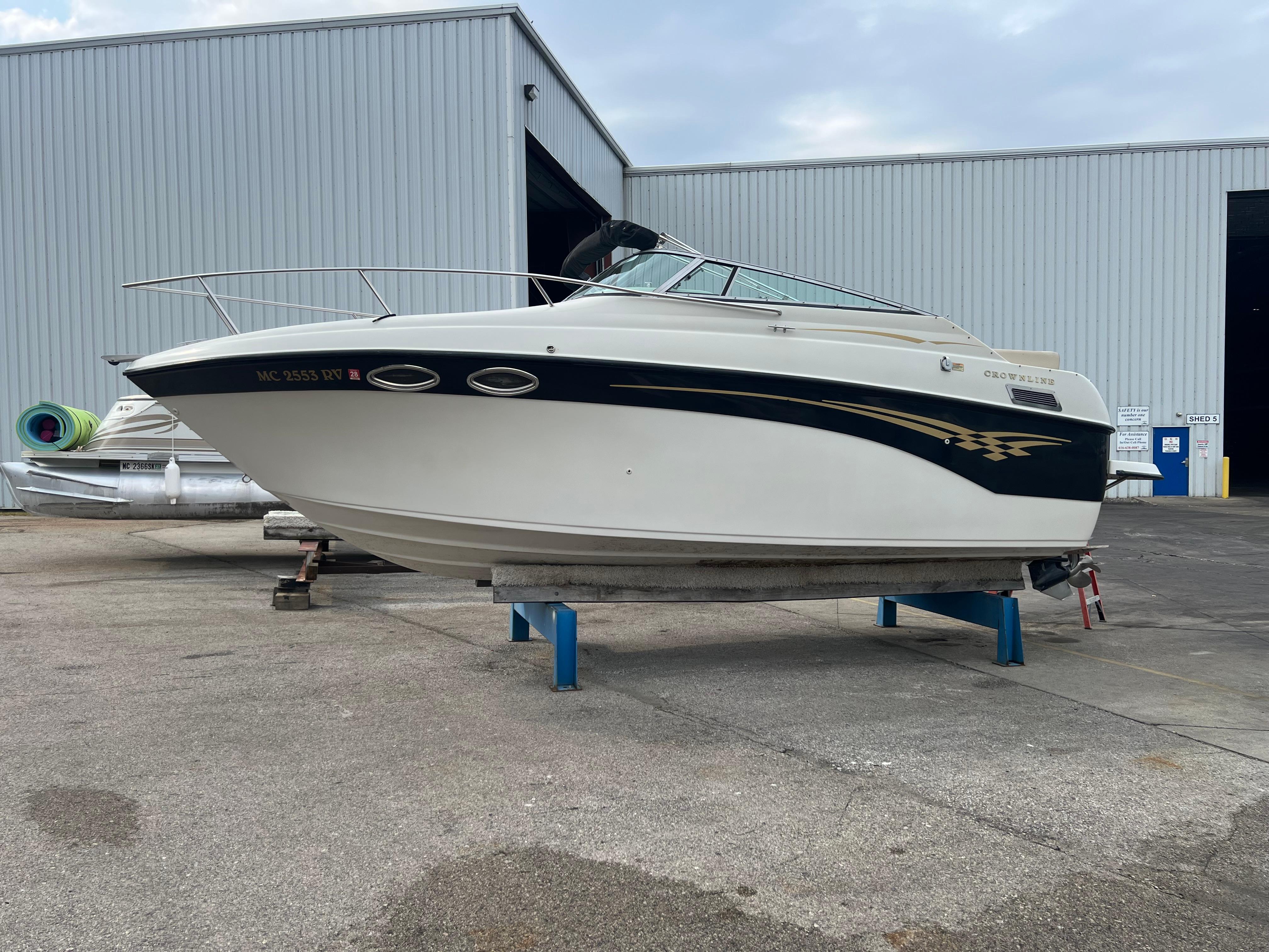 Crownline 242 CR 2000 Crownline 242 CR boat on stands outside a large warehouse.